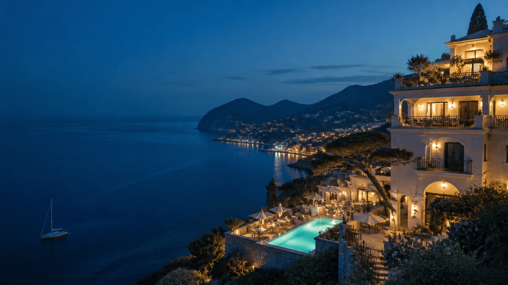 Coastal hotel terrace glowing at dusk above a calm sea